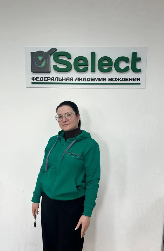 Сотрудница школы у вывески «Федеральная академия вождения» в офисе