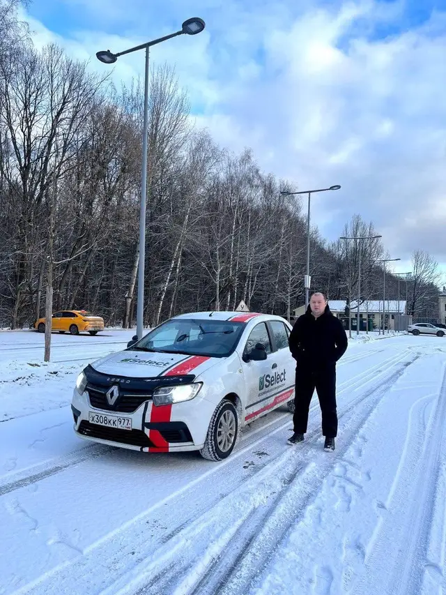 Инструктор рядом с Renault Logan на зимней дороге
