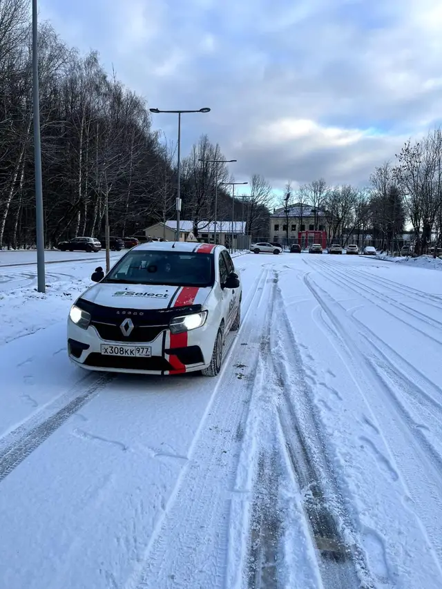 Renault Logan с включёнными фарами на зимней дороге